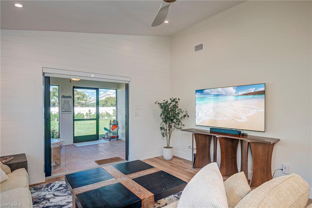 Living area featuring lofted ceiling, wood finished floors, recessed lighting, and a ceiling fan
