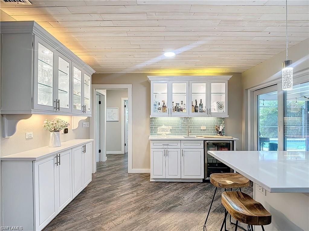 Kitchen with glass insert cabinets, wooden ceiling, pendant lighting, dark wood-style floors, and tasteful backsplash
