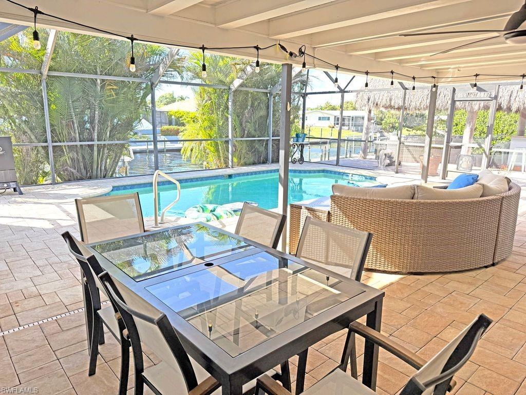 Swimming pool featuring a lanai, outdoor dining space, a sunroom, and a patio area