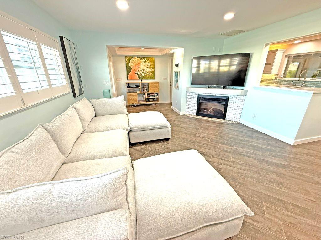 Living area with recessed lighting, a glass covered fireplace, and wood finished floors