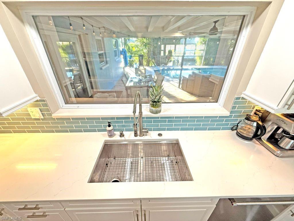 Kitchen view of light stone countertops, tasteful backsplash, and white cabinets