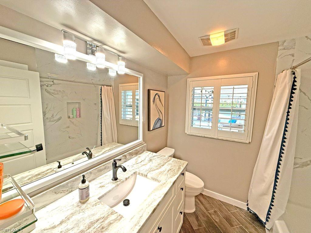 Full bathroom featuring wood tiled floors, vanity, and shower / bath combo