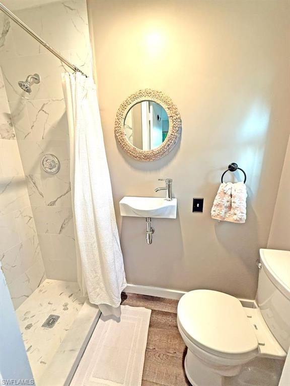 Full bathroom featuring a shower stall and baseboards