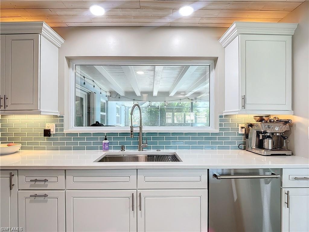 Kitchen with dishwasher, decorative backsplash, light stone countertops, white cabinetry, and recessed lighting