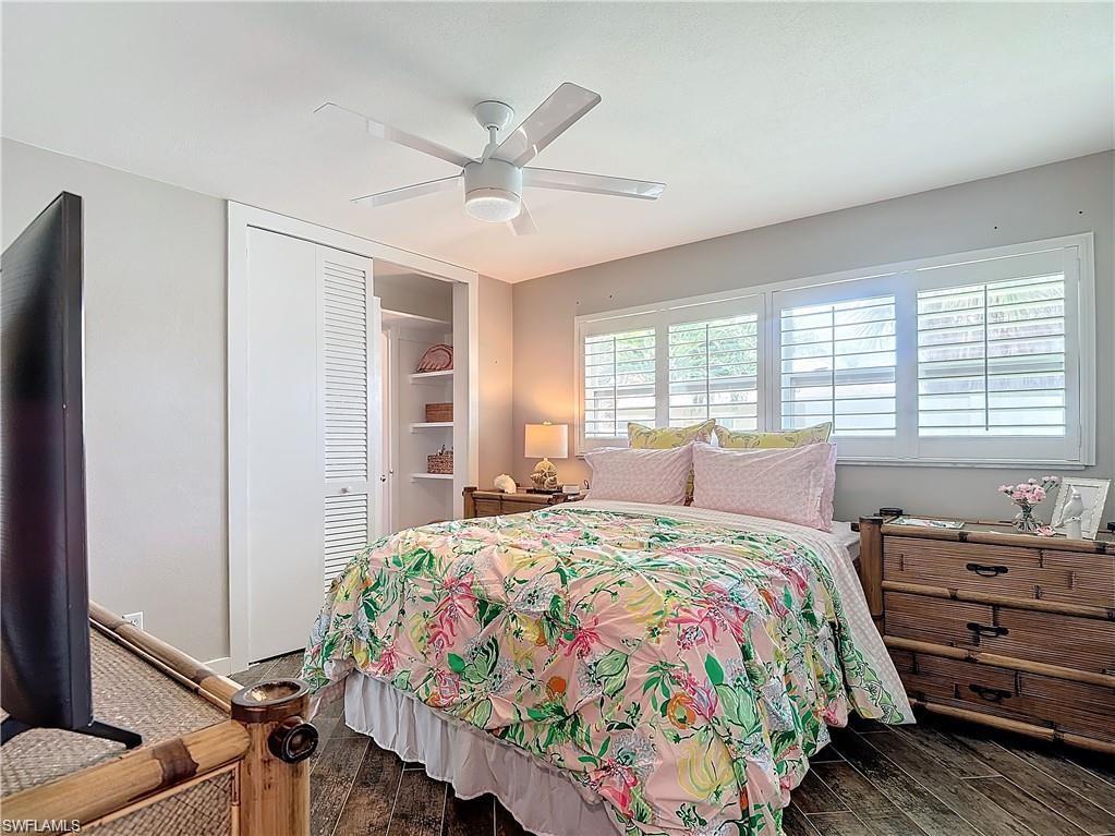 Bedroom with dark wood-style floors, a closet, and a ceiling fan