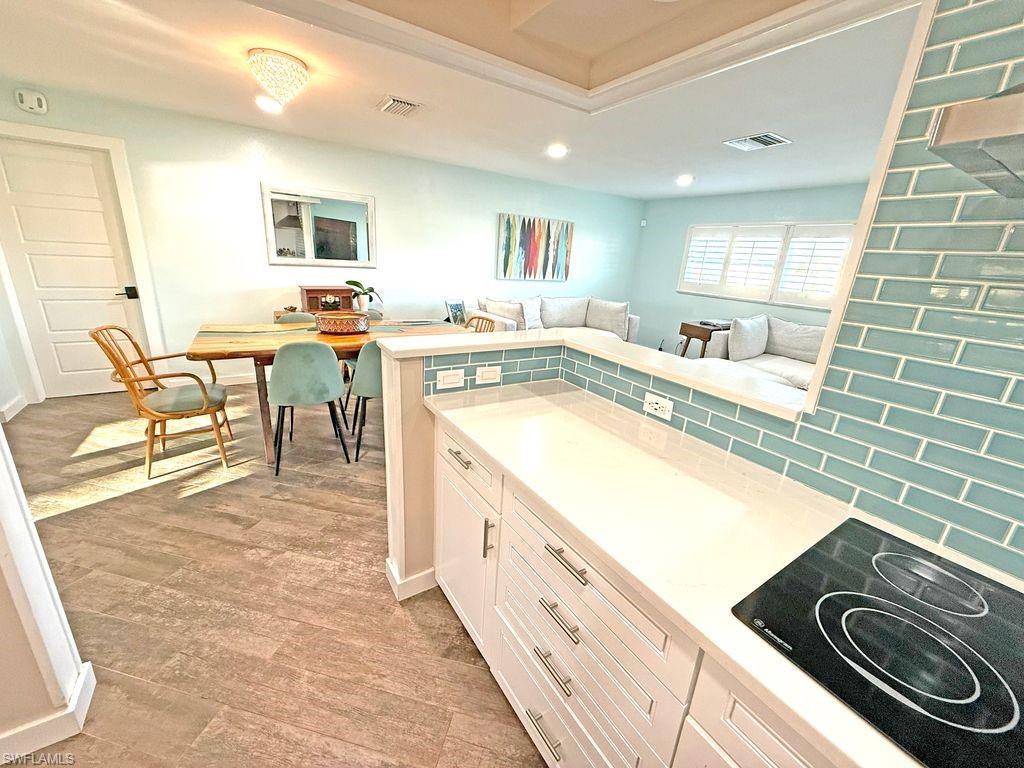 Kitchen featuring white cabinets, black electric cooktop, recessed lighting, tasteful backsplash, and light wood finished floors