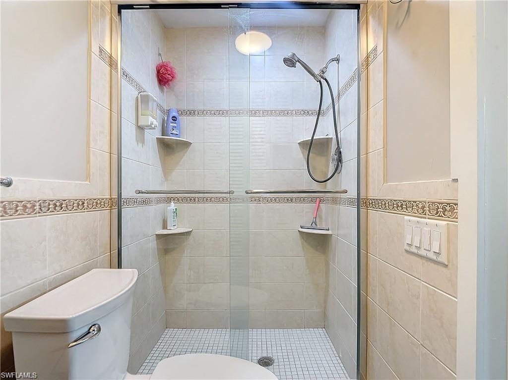 Bathroom featuring tile walls and a shower stall