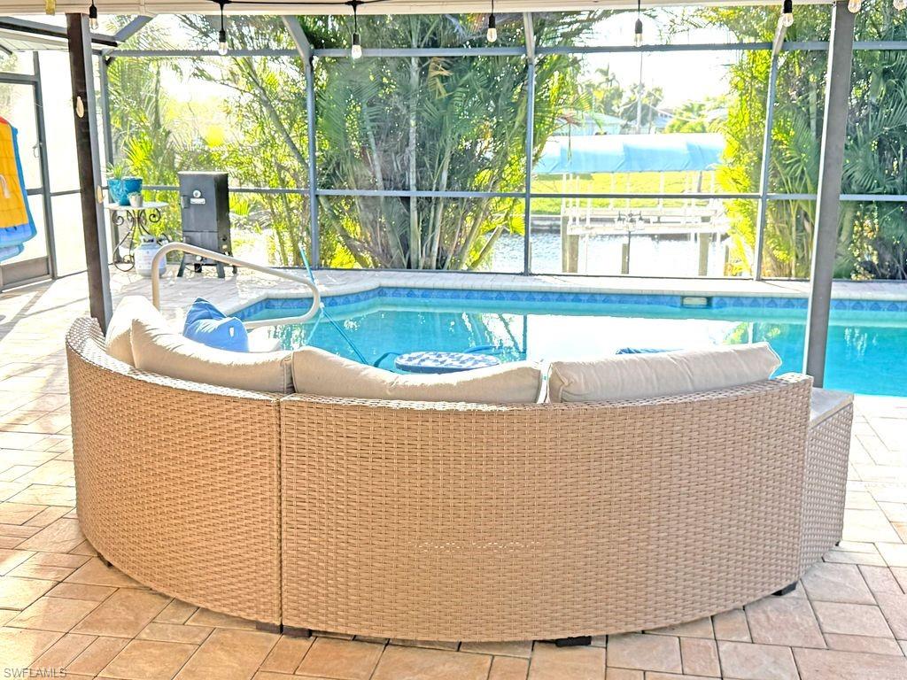 Outdoor pool featuring glass enclosure, a patio area, and a sunroom