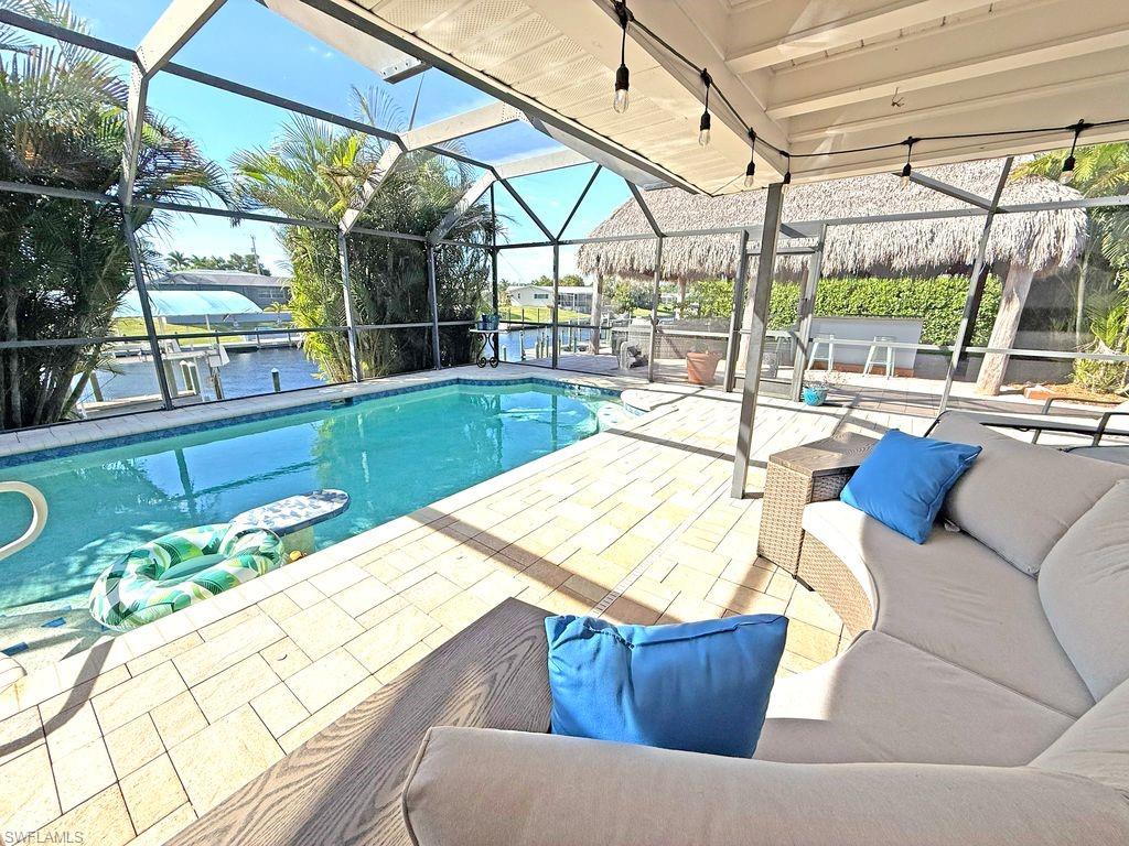 Swimming pool featuring a lanai, a water view, a sunroom, and a patio