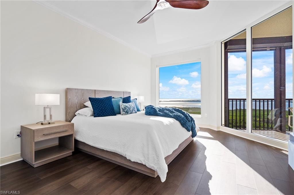 Bedroom with a water view, dark wood-style floors, crown molding, a ceiling fan, and access to exterior