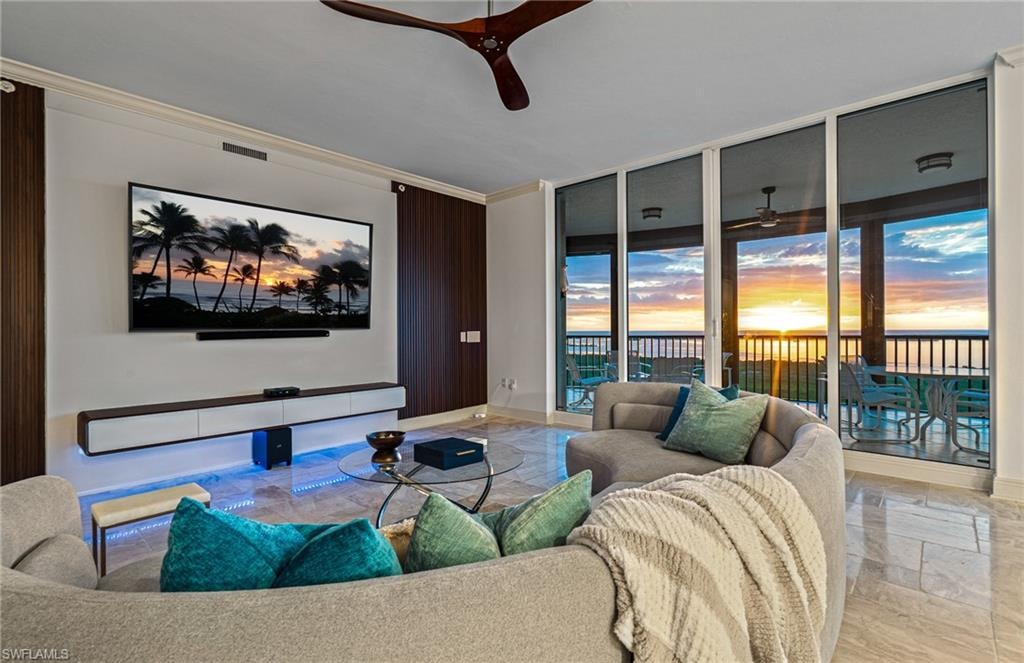 Living area with ornamental molding, light marble finish floors, floor to ceiling windows, and ceiling fan