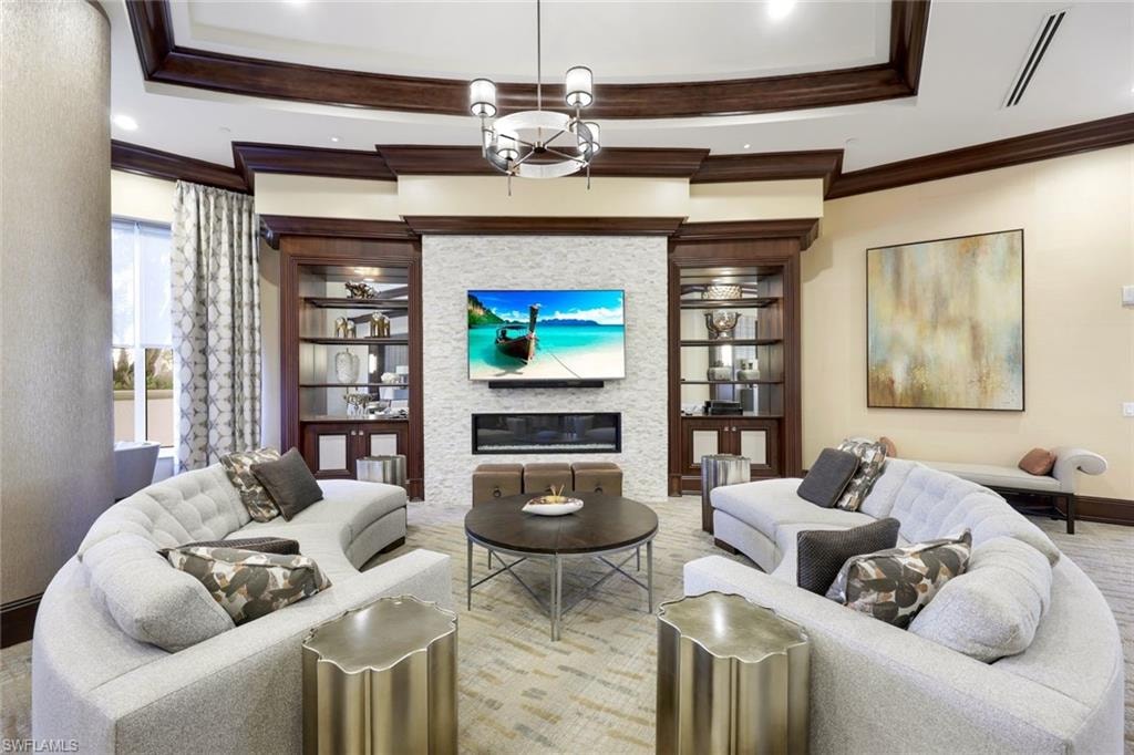 Living room with a large fireplace, a chandelier, and crown molding