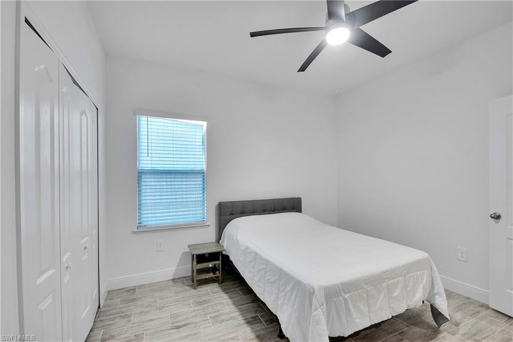 Bedroom with wood tiled floors, a ceiling fan, and a closet