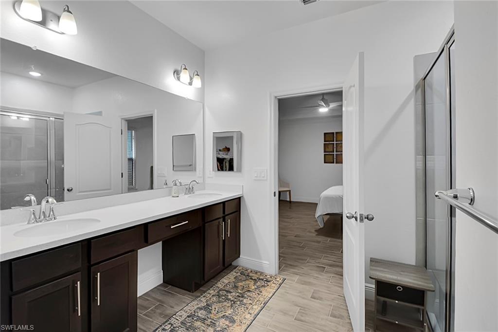 Ensuite bathroom with a stall shower, double vanity, and wood tiled floors