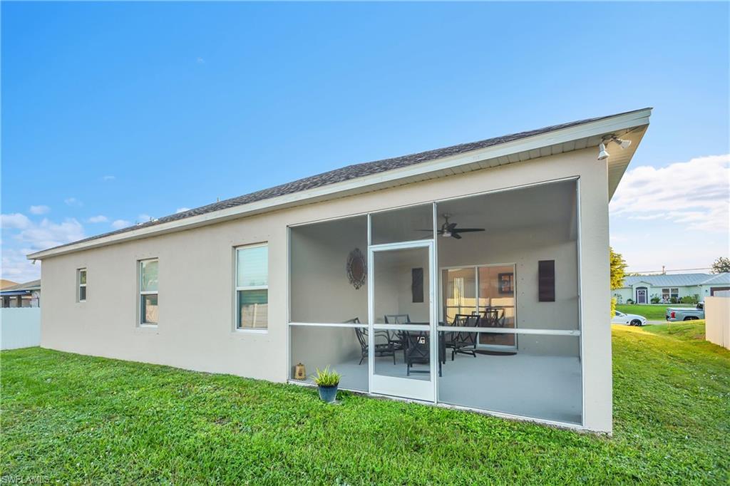 Back of house featuring a sunroom, ceiling fan, a yard, and stucco siding