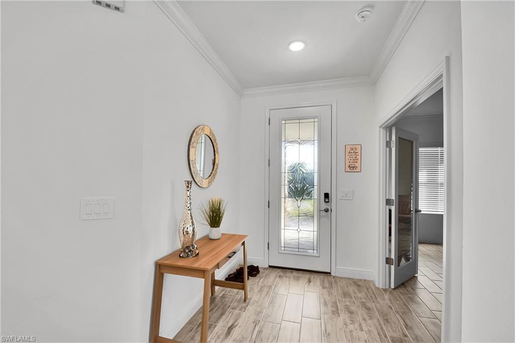 Doorway with crown molding and wood tiled floors