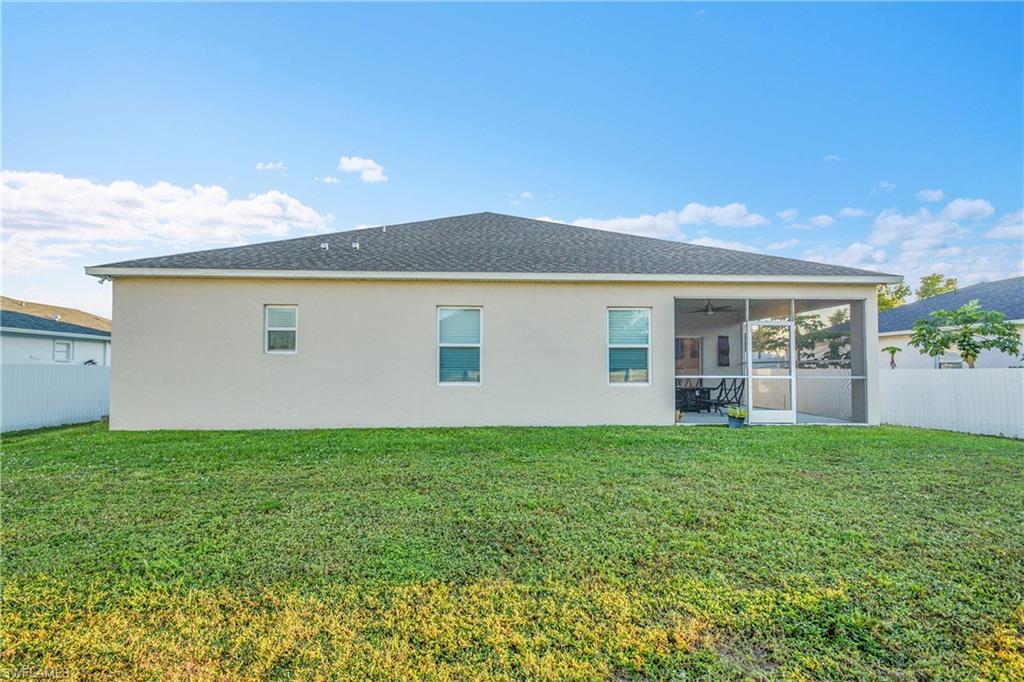 Rear view of property featuring stucco siding, roof with shingles, and a sunroom