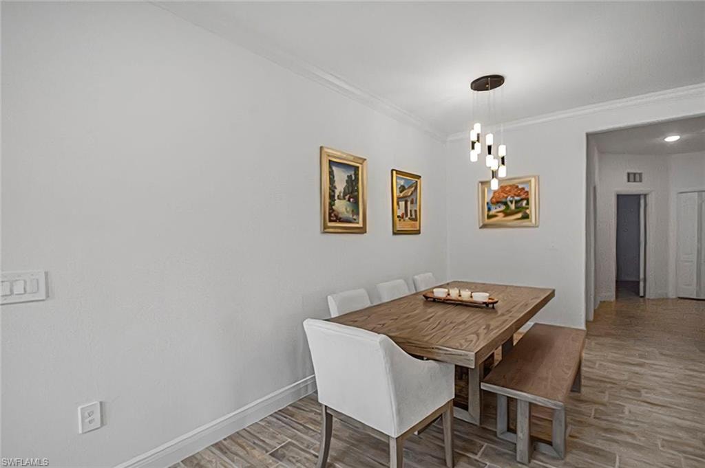 Dining room with light wood-type flooring, ornamental molding, and a chandelier