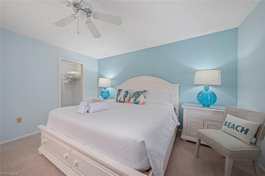 Carpeted bedroom featuring a spacious closet, a textured ceiling, and a ceiling fan