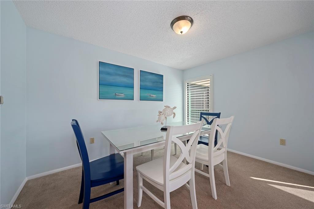 Carpeted dining area with a textured ceiling and baseboards