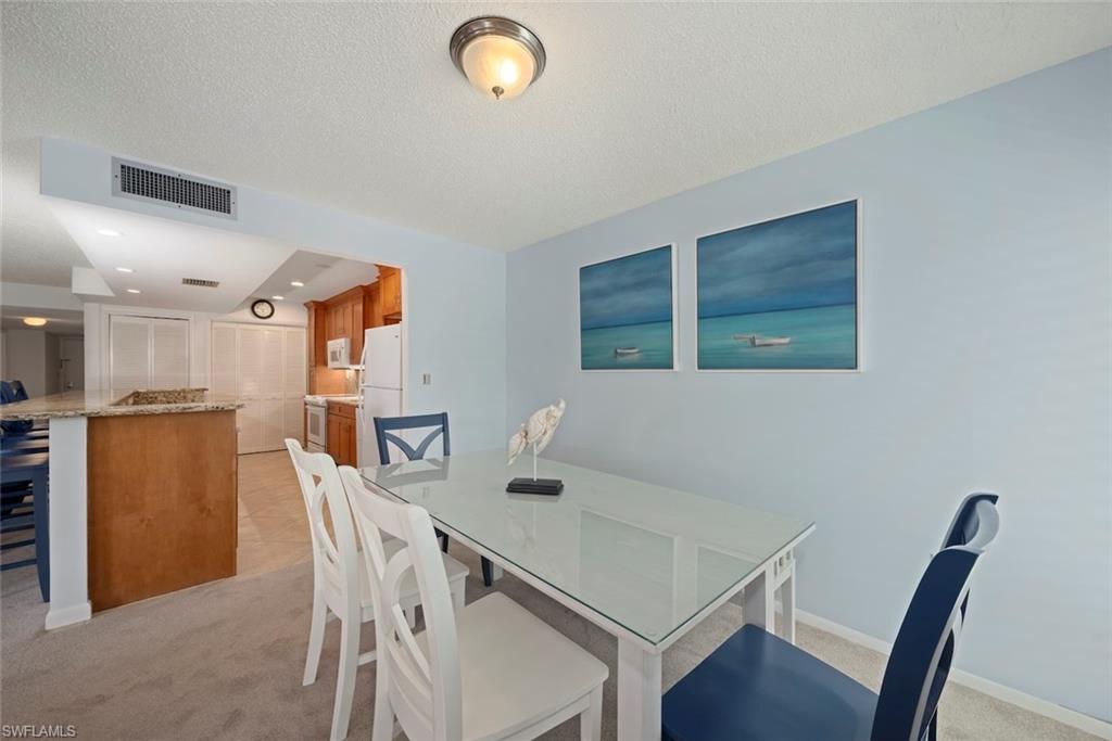 Dining space featuring light colored carpet and a textured ceiling