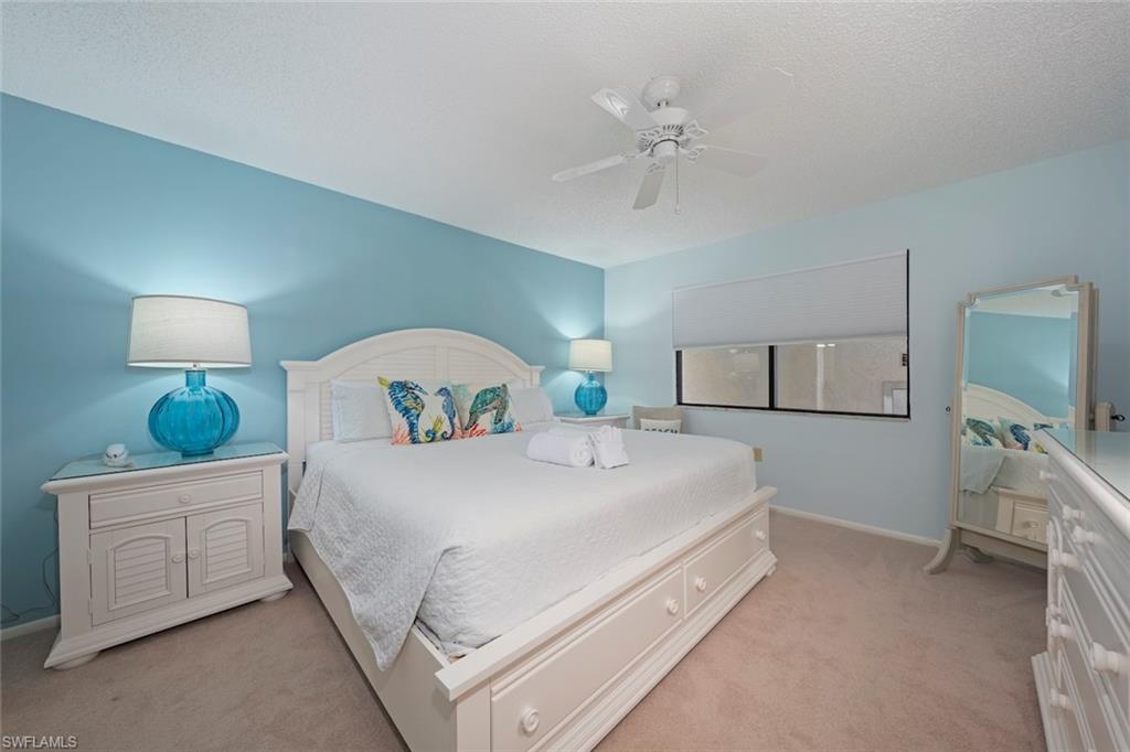 Bedroom featuring ceiling fan, light colored carpet, and a textured ceiling