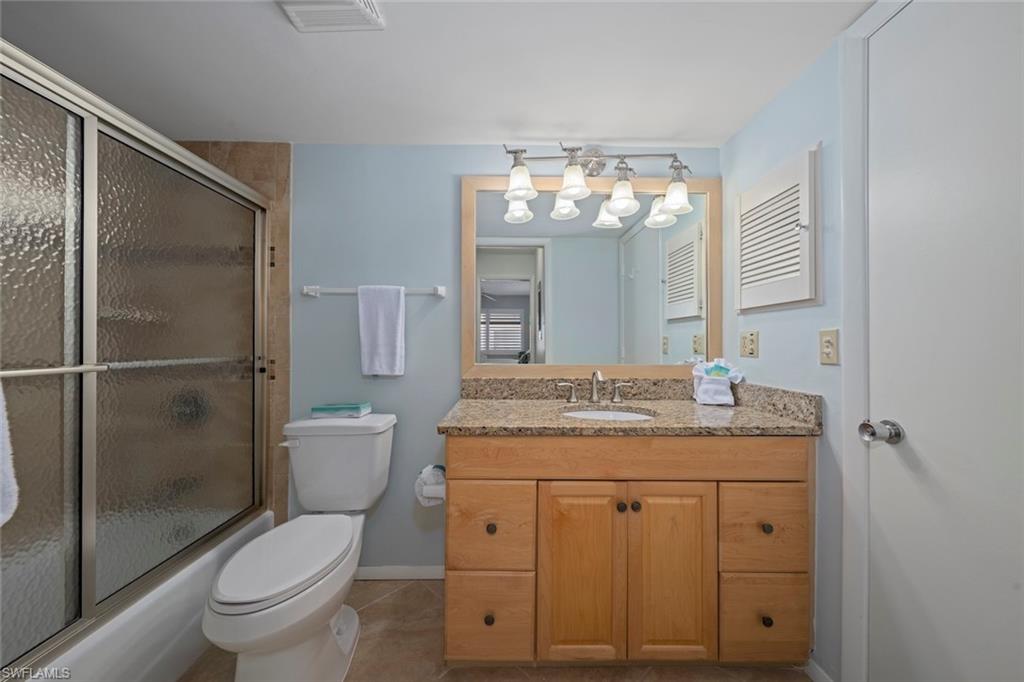 Full bathroom featuring vanity, enclosed tub / shower combo, and light tile patterned floors