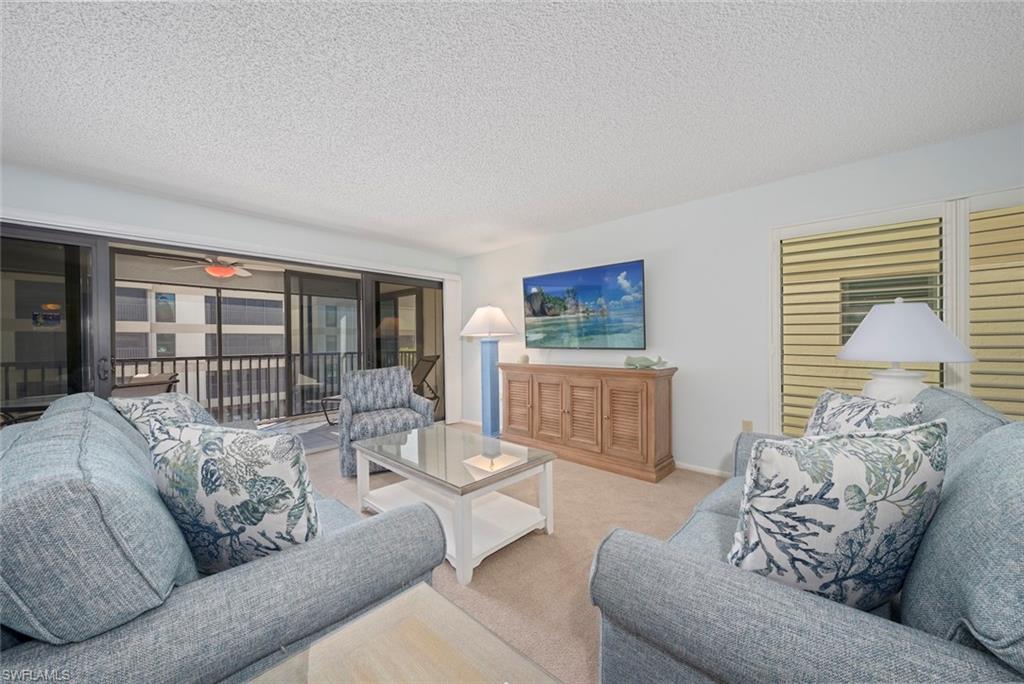 Living area with a textured ceiling, carpet, and ceiling fan