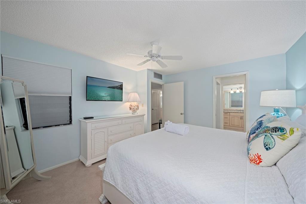 Bedroom featuring light carpet, ceiling fan, a textured ceiling, and ensuite bathroom