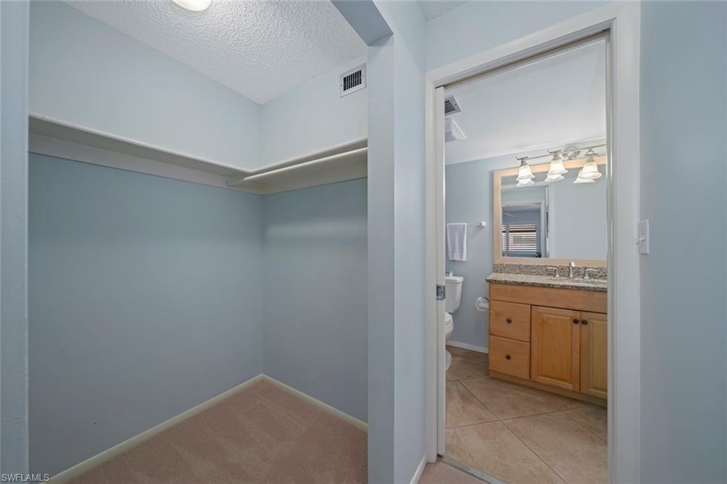 Walk in closet with light colored carpet and light tile patterned floors