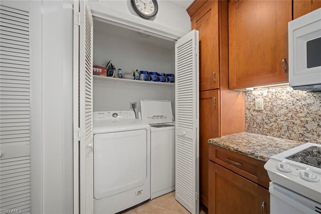 Washroom with light tile patterned flooring and washer and dryer