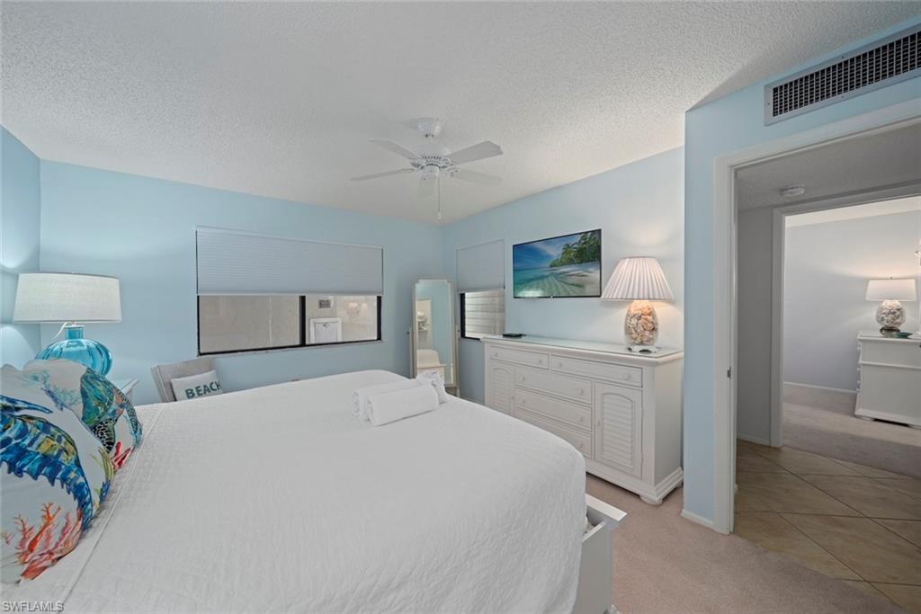 Bedroom with light colored carpet, ceiling fan, a textured ceiling, and light tile patterned floors