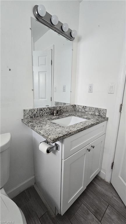Half bathroom with vanity and wood finish floors