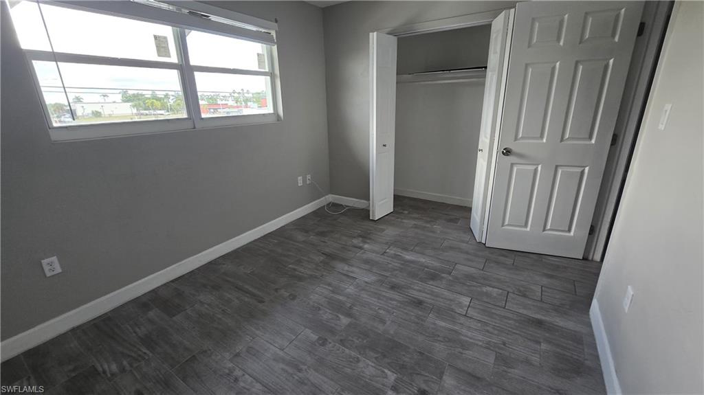 Unfurnished bedroom with dark wood-style floors and a closet