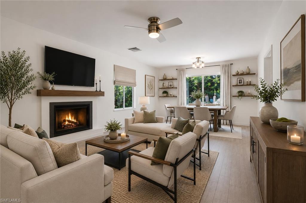 Virtually staged living and dining room, highlighting the wood burning fireplace. Access to the kitchen and patio/pool area.