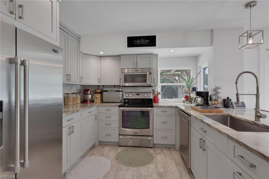 Beautifully updated kitchen with Quartz Countertops, gray wood shaker cabinets, stainless steel appliances, and a large walk in pantry