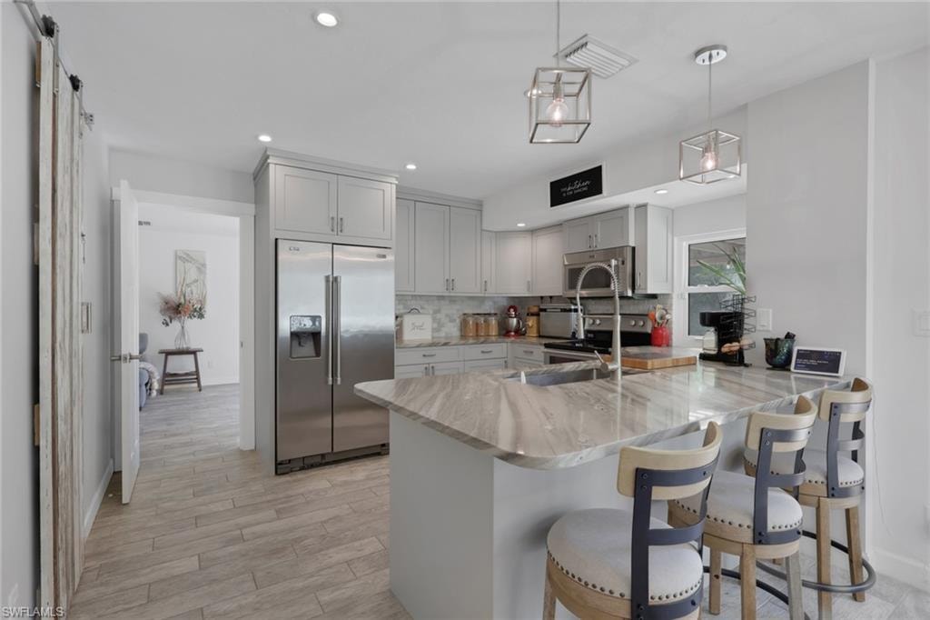 Beautifully updated kitchen with Quartz countertops, Gray wood shaker cabinets, glass backsplash, newer appliances, deep kitchen sink, seating area, perfect view of the pool/patio area, and a large walk in pantry with custom barn door.