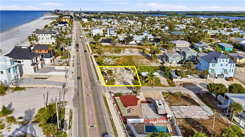 Aerial view of residential area with property boundaries highlighted and expansive beach - Virtually Edited Image
