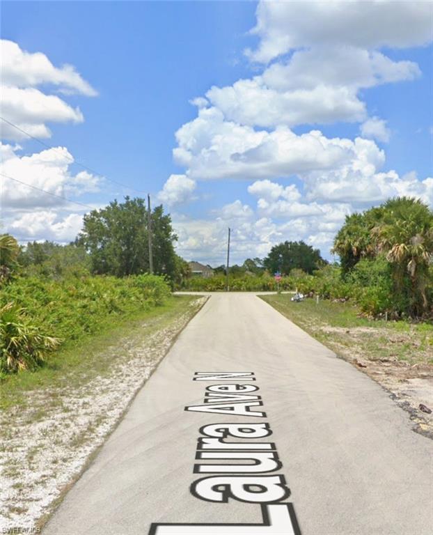 View of asphalt road featuring view of wooded area