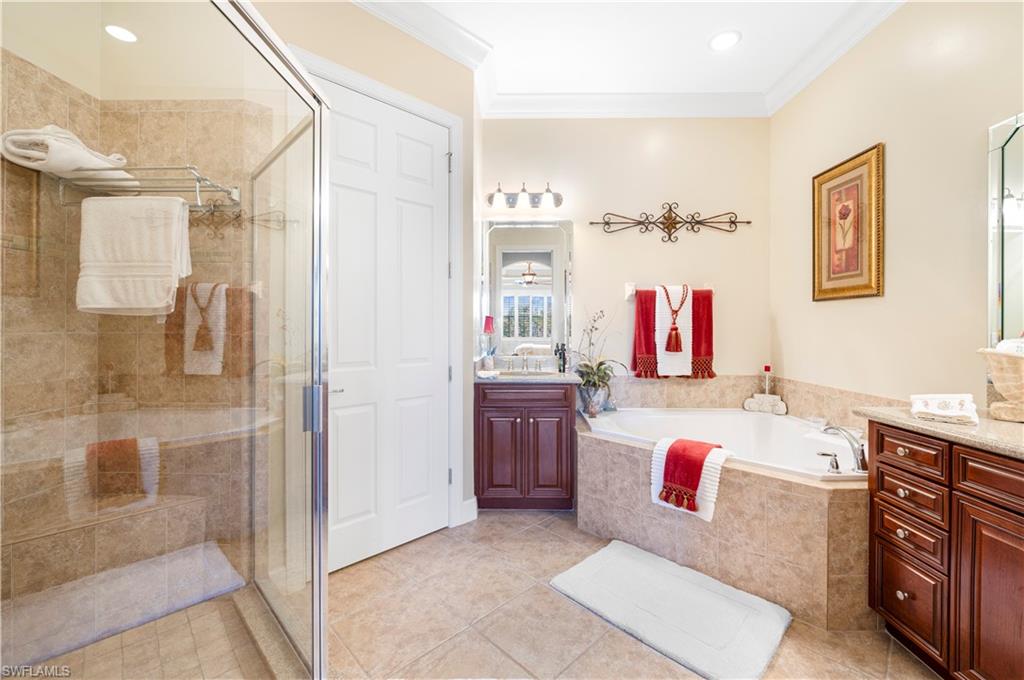 Bathroom with vanity, a bath, a stall shower, crown molding, and light tile patterned floors