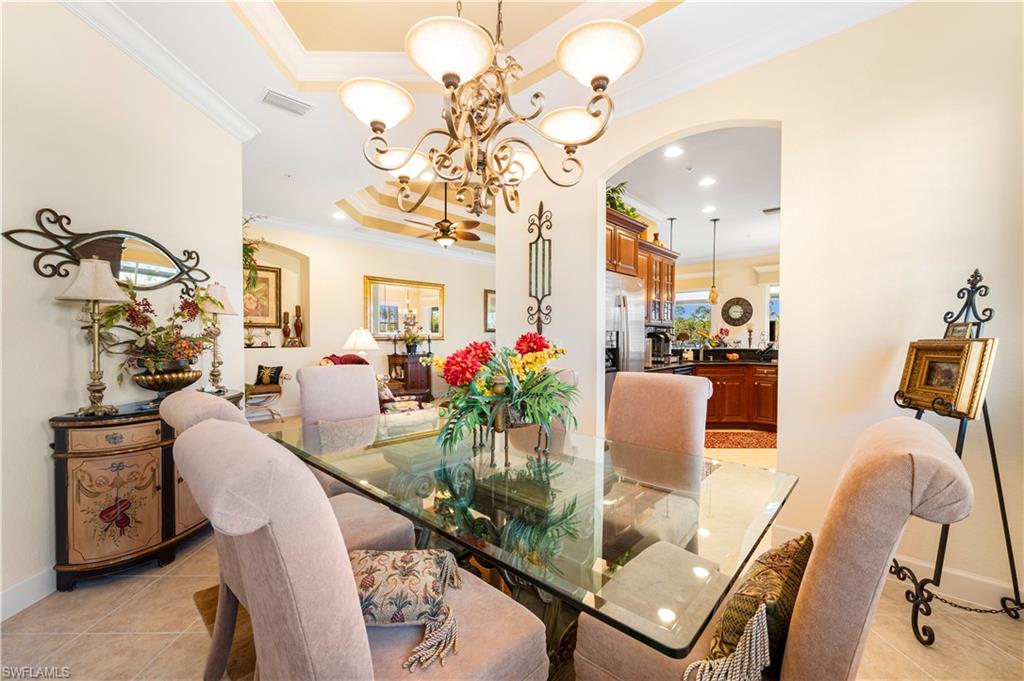 Dining space featuring light tile patterned floors, crown molding, arched walkways, a chandelier, and recessed lighting