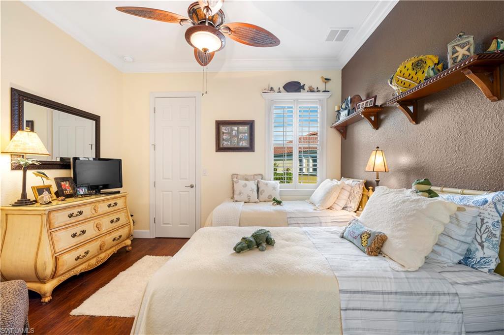 Bedroom with dark wood-style floors, crown molding, and a ceiling fan
