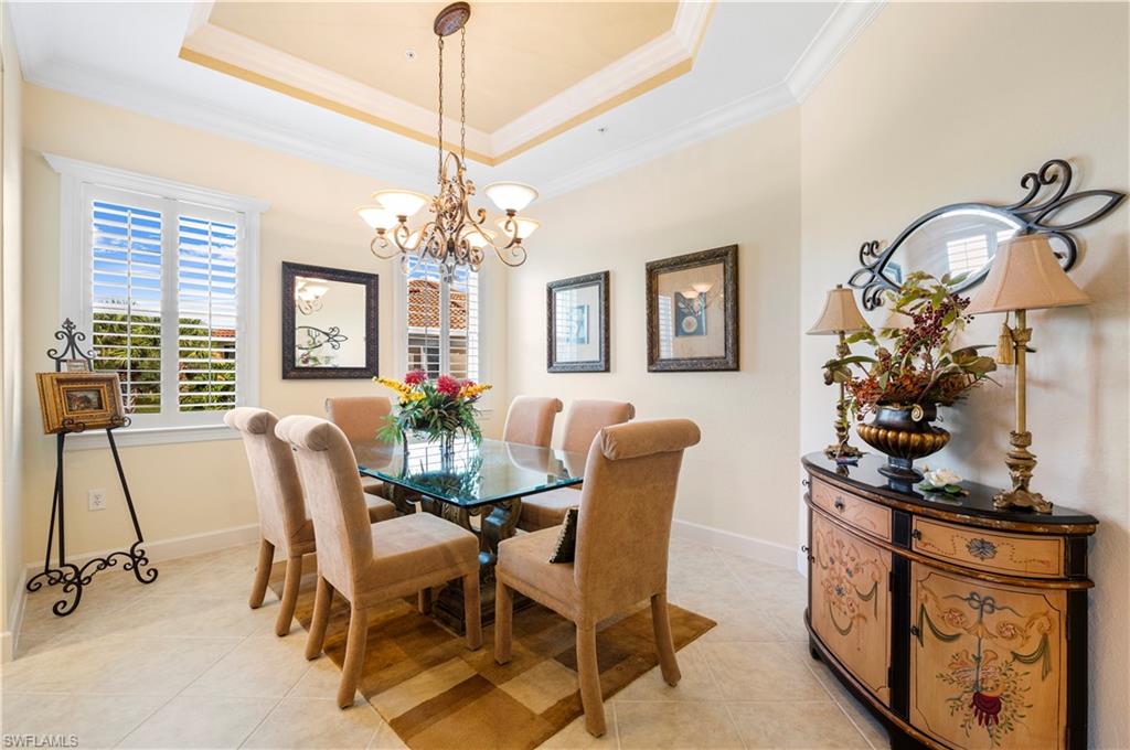 Dining area featuring a raised ceiling, light tile patterned floors, crown molding, and a chandelier