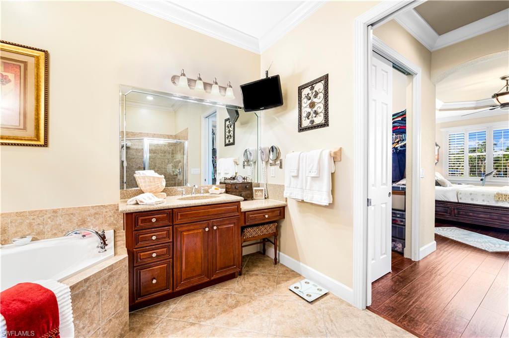 Bathroom with ornamental molding, a shower stall, vanity, a garden tub, and ensuite bathroom