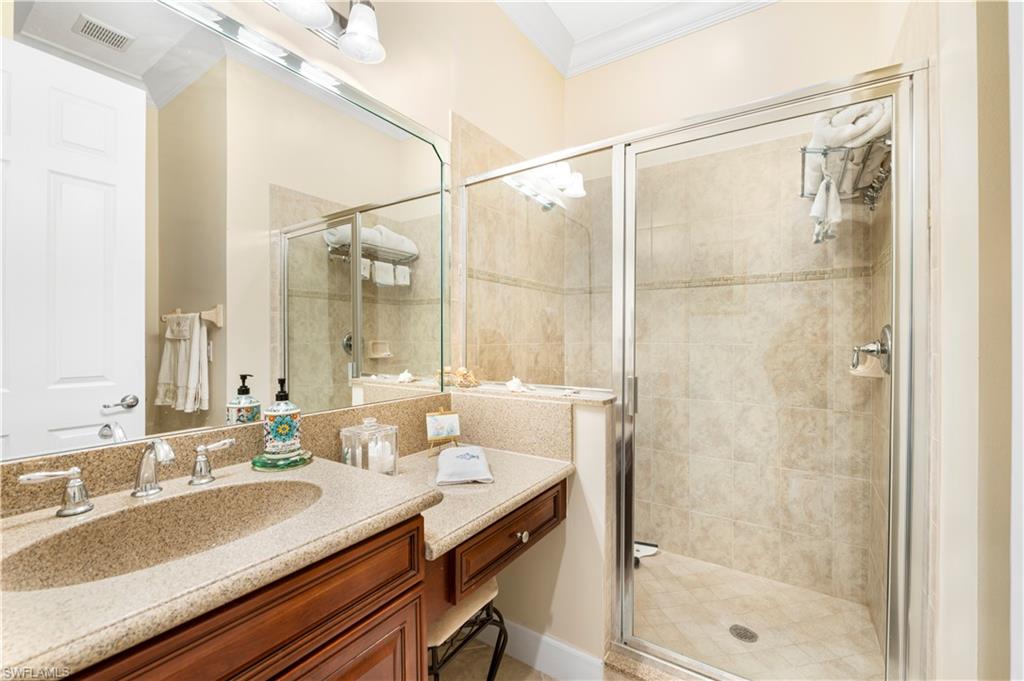 Bathroom featuring vanity, crown molding, and a shower stall