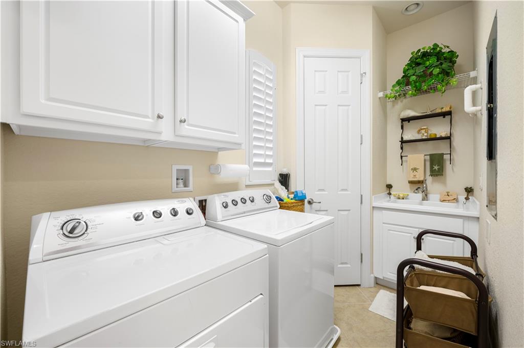 Laundry room with cabinet space, light tile patterned floors, and separate washer and dryer