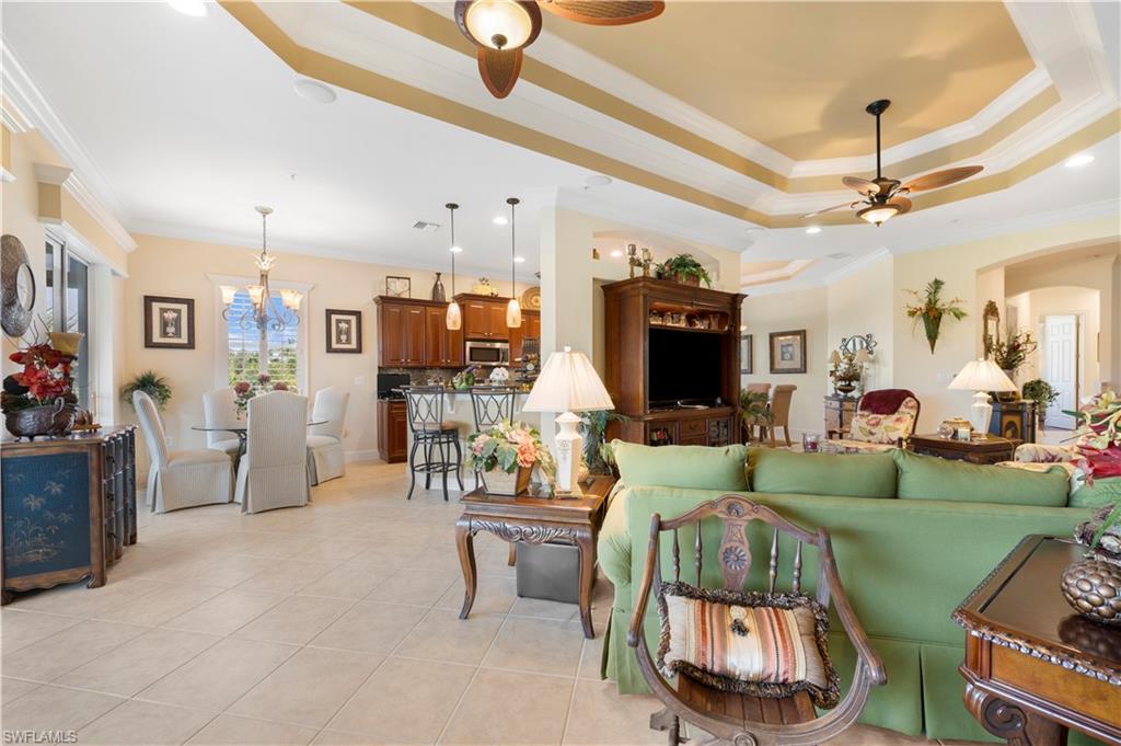 Living room with a raised ceiling, crown molding, a ceiling fan, light tile patterned flooring, and recessed lighting