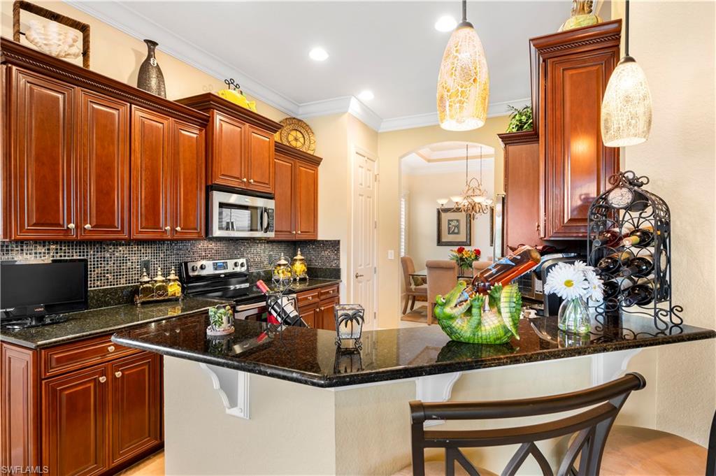 Kitchen with a kitchen breakfast bar, arched walkways, appliances with stainless steel finishes, a peninsula, and ornamental molding