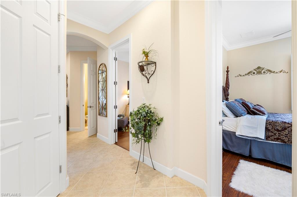 Corridor featuring crown molding, arched walkways, and light tile patterned floors