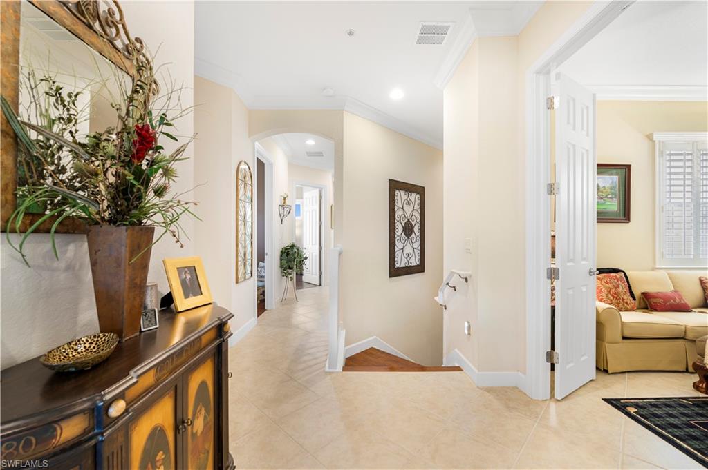 Hall featuring ornamental molding, arched walkways, and light tile patterned floors